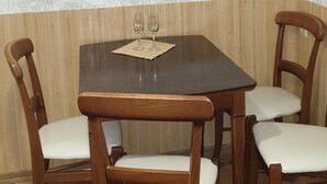 A dining area with a wooden table and four chairs, a picture on the wall, and a patterned wallpaper. - Apartment Levanevskogo 7-53 (Odesa)