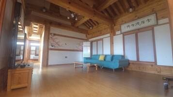 Una habitación amplia con techo de madera, un sofá azul, una mesita pequeña y una pared con un panel decorativo.