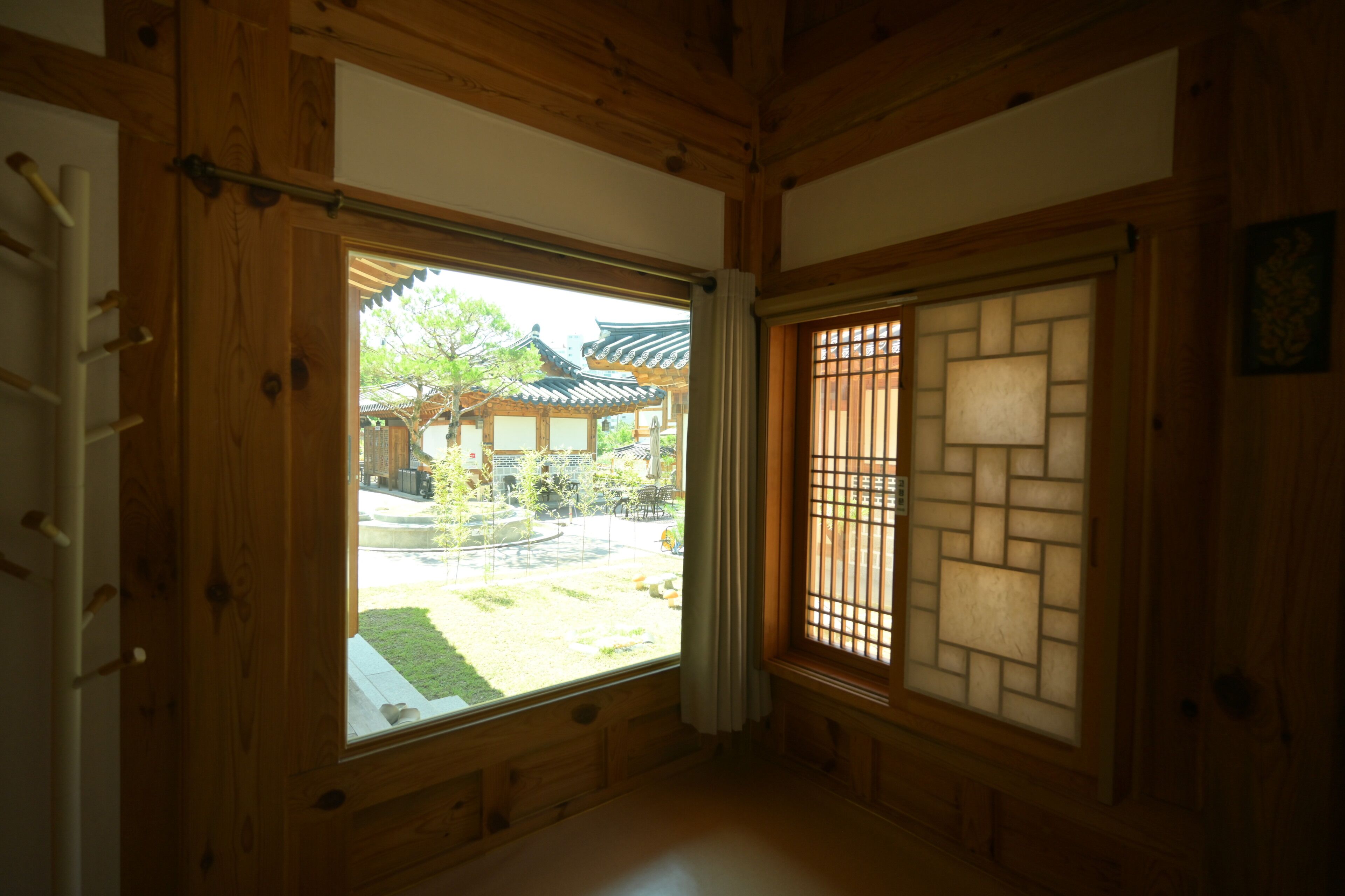 Una habitación japonesa tradicional con suelo de tatami, un shoji y vista a un patio con una edificación tradicional.