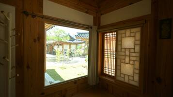 Una habitación japonesa tradicional con suelo de tatami, un shoji y vista a un patio con una edificación tradicional.