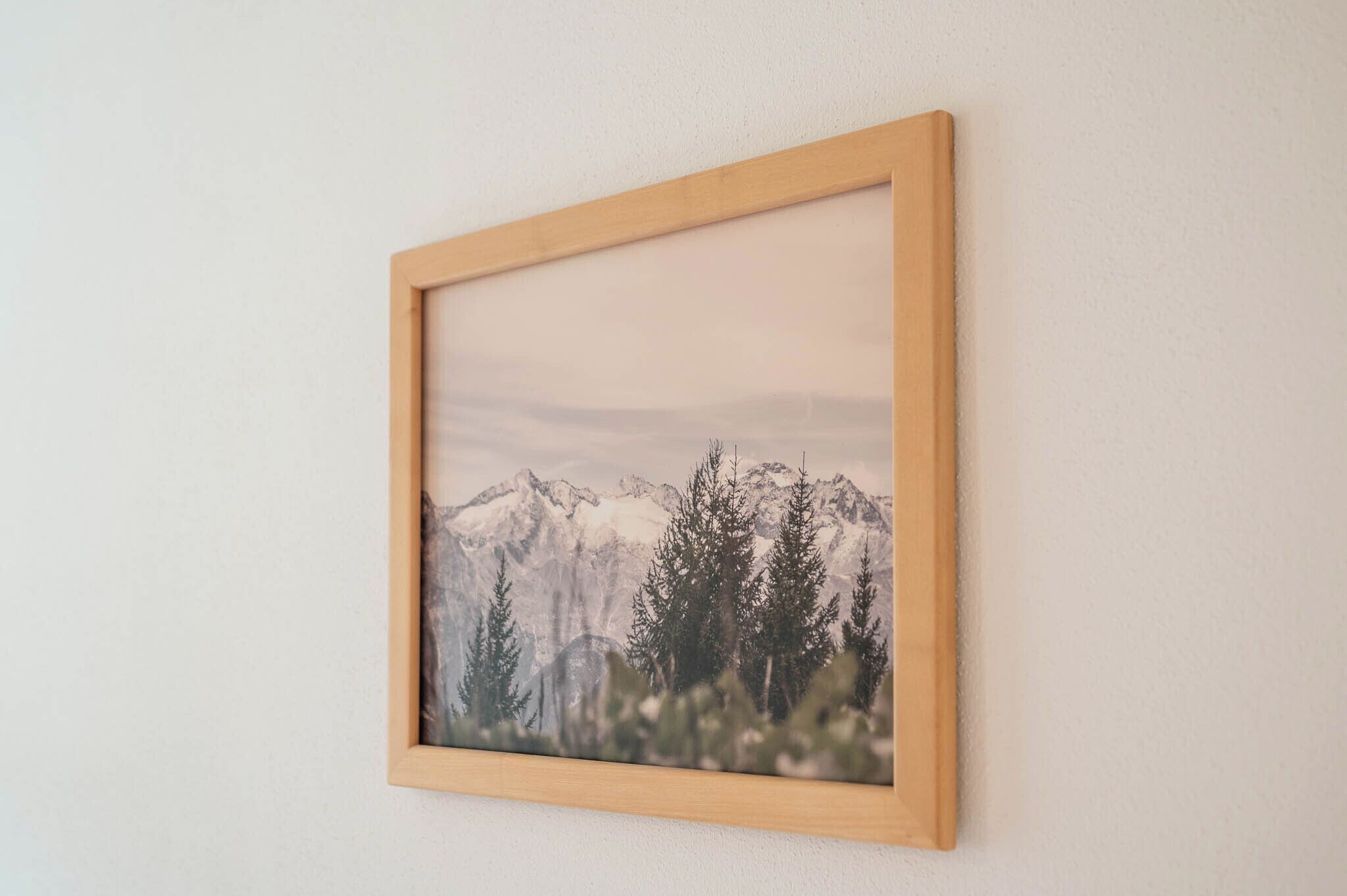 Un tableau encadré représentant un paysage de montagne, accroché au mur.