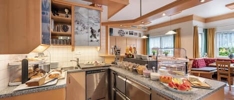 A modern kitchen with a central island, stainless steel appliances, and a variety of breakfast items.
