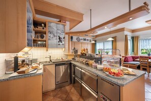 Una cocina moderna con una isla central, electrodomésticos de acero inoxidable y diversas opciones para el desayuno.
