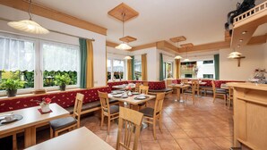 A restaurant with wooden furniture, large windows, and potted plants. - Pension Posauner Dorfgastein (Dorfgastein)