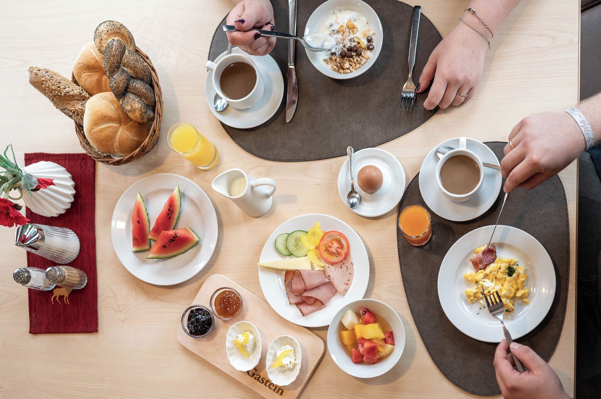 Une table dressée pour le petit-déjeuner, avec différents plats, notamment des toasts, des fruits, des œufs et du café.