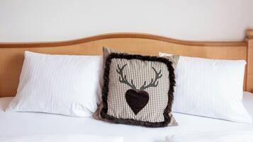 A bed with two white pillows and a decorative pillow with a deer head and heart design.