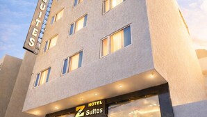 Un edificio de hotel con un cartel que dice 'HOTEL SUITES' y una persona parada en la entrada.