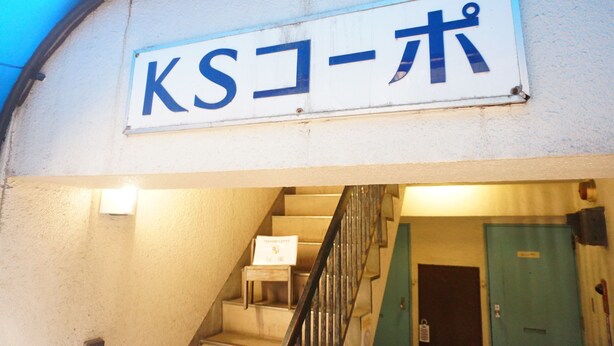Un panneau avec des caractères japonais, un escalier et une porte.