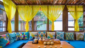 A cozy seating area with a wooden table, colorful cushions, and yellow curtains. - Li Jiang Tang Feng Yard No.1 (Lijiang)