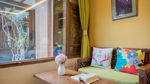 A wooden table with a vase and an open book, a sofa with colorful pillows, and a framed picture on the wall. - Li Jiang Tang Feng Yard No.1 (Lijiang)