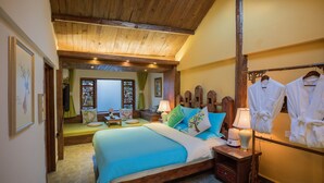 A bedroom with a wooden ceiling, a bed with blue bedding, a bedside table with a lamp, and a rack with white robes. - Li Jiang Tang Feng Yard No.1 (Lijiang)
