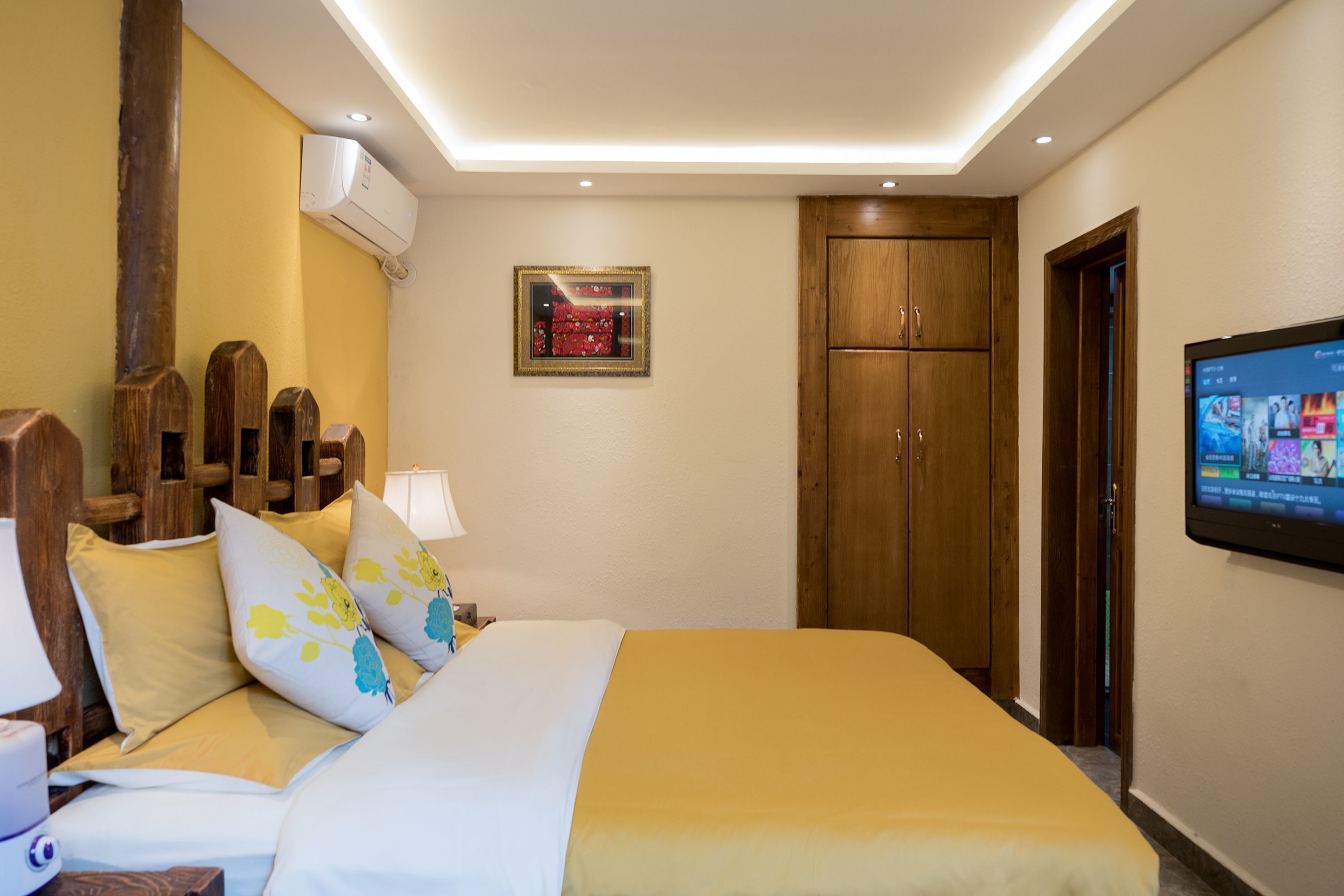 Ein Hotelzimmer mit einem Bett, einem Holzkopfende, einem Fernseher und einem Kleiderschrank.