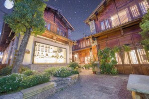 A courtyard with wooden buildings, a large illuminated mural, and potted plants. - Li Jiang Tang Feng Yard No.1 (Lijiang)