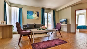 Una sala de estar moderna con un sofá, dos sillones, una mesa de centro y un televisor.