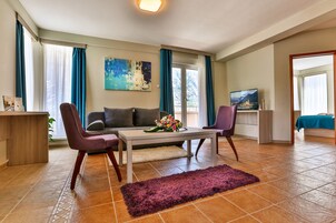 Una sala de estar moderna con un sofá, dos sillones, una mesa de centro y un televisor.