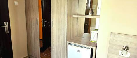 Una cocina compacta con refrigerador integrado, una pequeña encimera y una puerta que da a otra habitación.