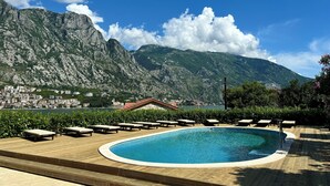 A pool area with lounge chairs and a view of mountains.