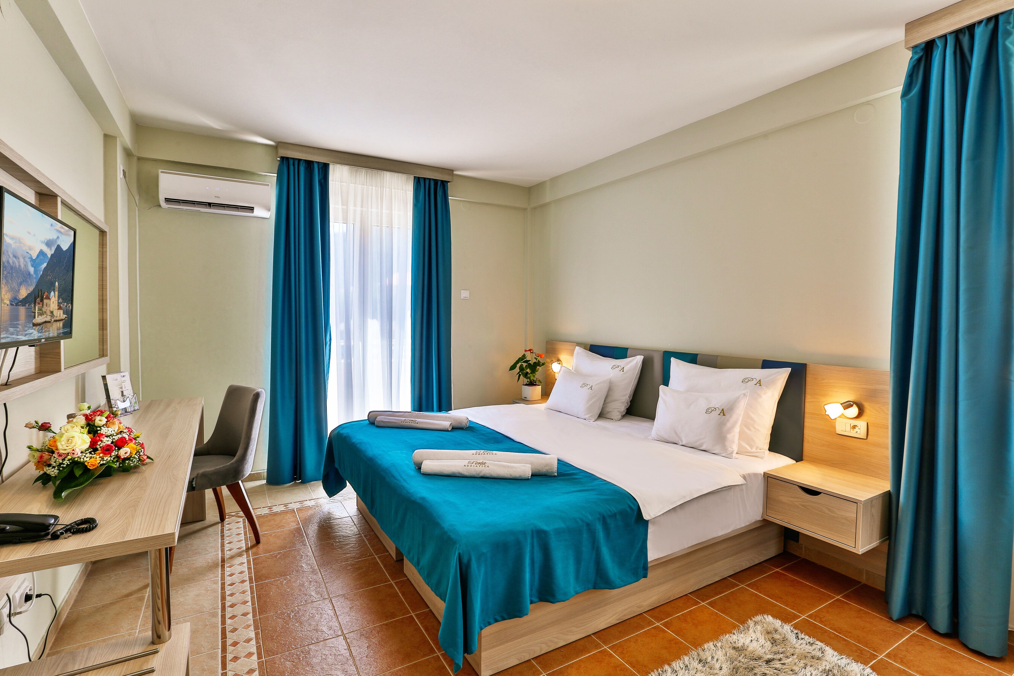 Habitación de hotel con cama, escritorio, silla, mesita de noche y aire acondicionado instalado en la pared.