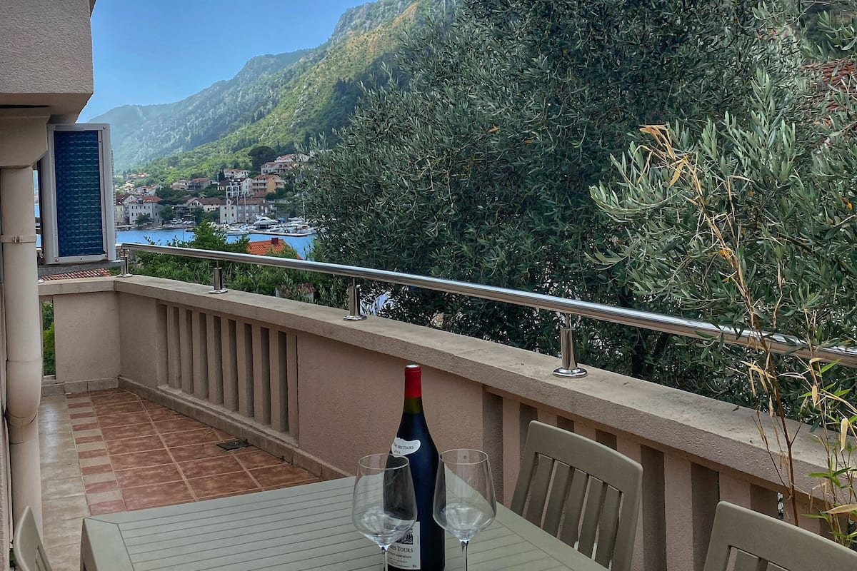 Un balcon avec une table, deux verres à vin, une bouteille de vin et un livre.