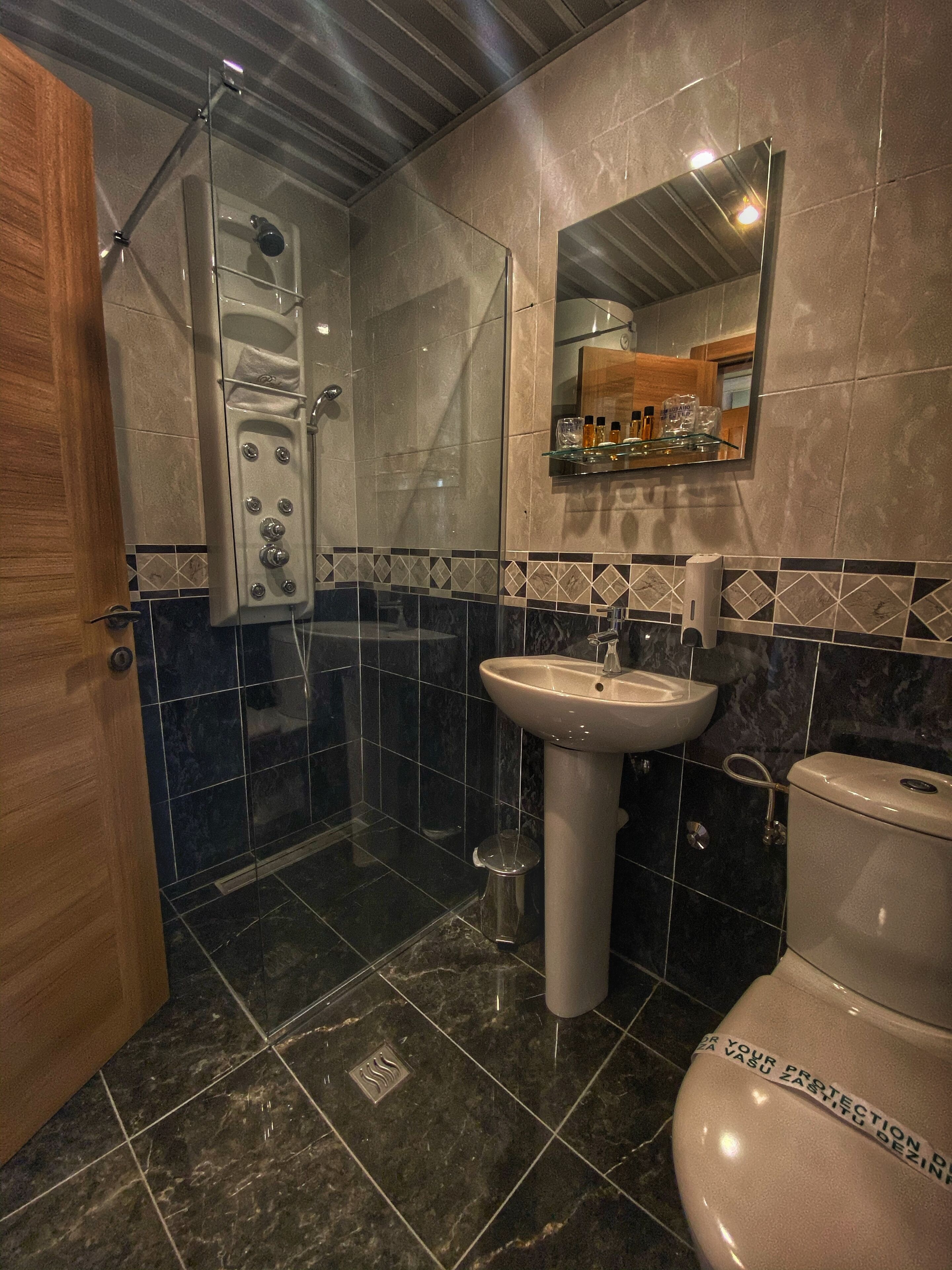A bathroom with a glass-enclosed shower, a pedestal sink, and a toilet.