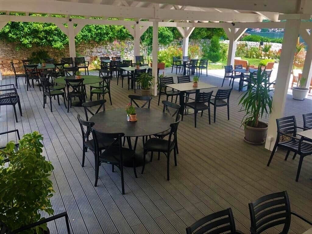 Un espace extérieur aménagé en terrasse, avec plusieurs tables et chaises, entouré d’une structure de pergola blanche.
