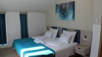Una cama bien hecha con una colcha azul y blanca, un cabecero y una mesita de noche con cajón.