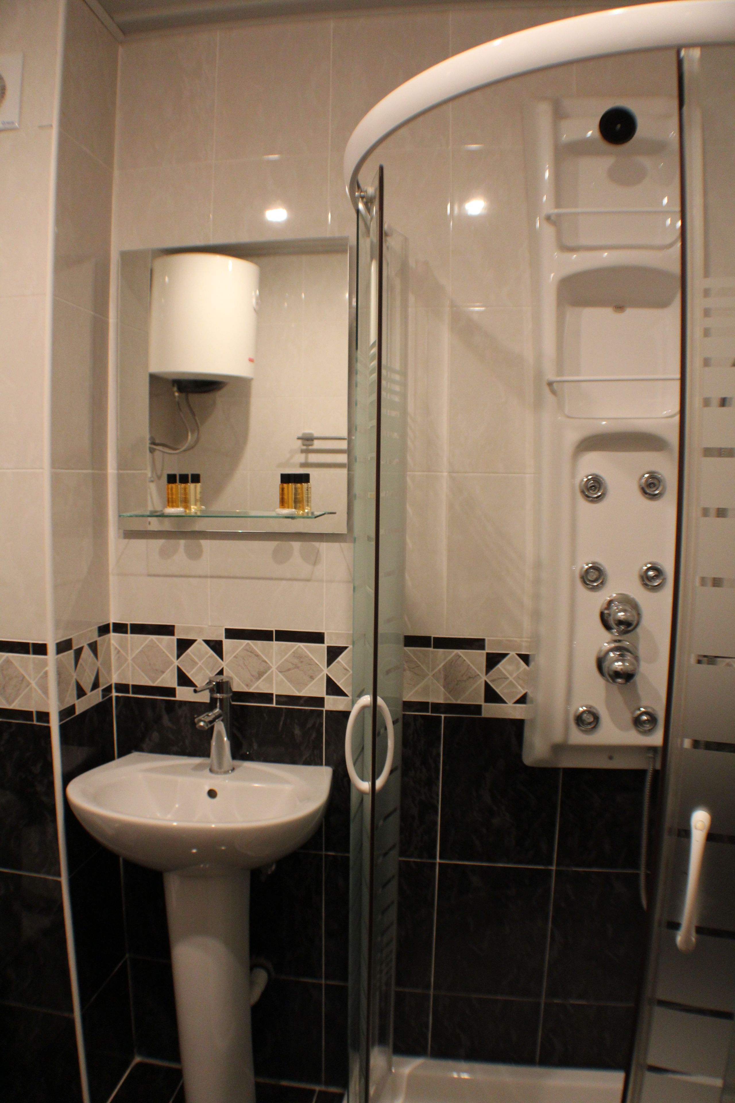 Une salle de bain avec une douche à parois de verre, un lavabo sur colonne et un miroir au-dessus du lavabo.