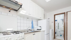 Eine Küche mit weißen Schränken, einem Gasherd, einer Spüle und einem Kühlschrank.