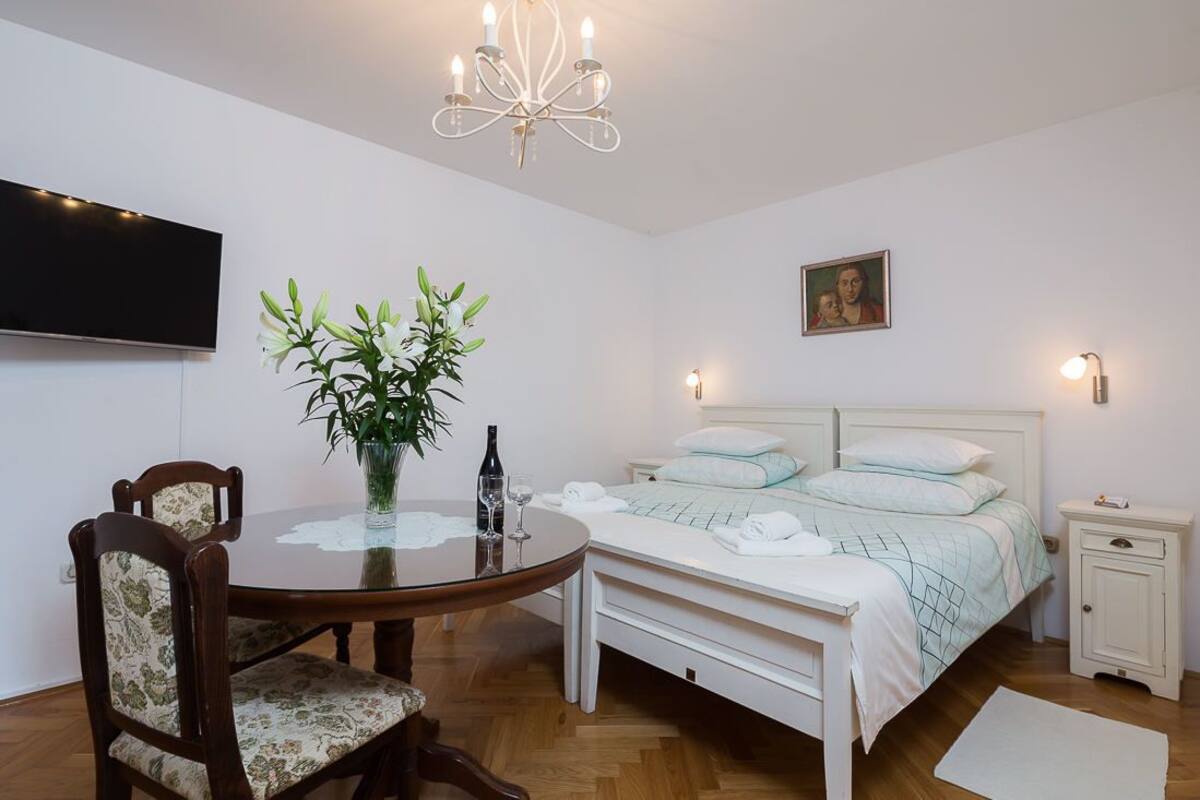 A bedroom with a bed, bedside table, nightstand, and a TV mounted on the wall.