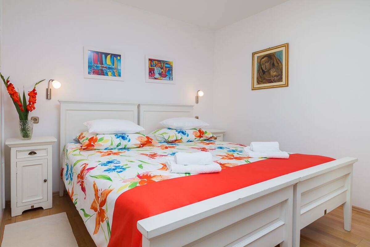 A neatly arranged bedroom with a bed, bedside tables, and artwork on the walls.
