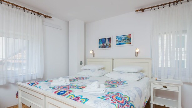 Ein ordentlich eingerichtetes Schlafzimmer mit einem Bett, Nachttischen und Vorhängen.