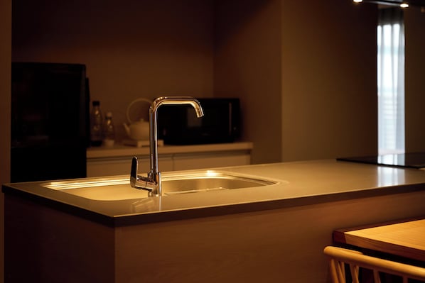 Une cuisine moderne dotée d’un évier en acier inoxydable, d’un four à micro-ondes et d’une table à manger en bois.
