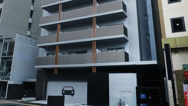 Un immeuble à plusieurs étages, doté d’une architecture moderne, avec une série de balcons et une entrée de garage.