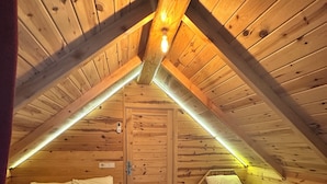 A cozy attic bedroom with two beds, wooden walls, and a sloped ceiling. - Nehir Bungalows (Camlihemsin)