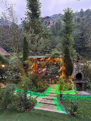 A garden with a stone structure, pathways, and surrounding greenery. - Nehir Bungalows (Camlihemsin)