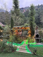 A garden with a stone structure, pathways, and surrounding greenery.