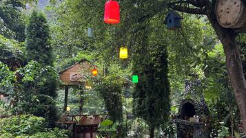 A garden with a wooden structure, a pond, and hanging birdhouses.
