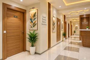 A hotel corridor with wooden doors, a reception desk, and framed artwork on the walls. - Hotel Royal Square, Ahmedabad (Ahmedabad)