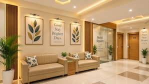 Een hotel lobby met een receptiebalie, twee banken, ingelijste kunstwerken en een bord met de tekst Hotel Square.