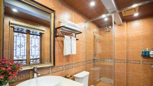 Et badeværelse med stor vask, toilet og brusebad.
