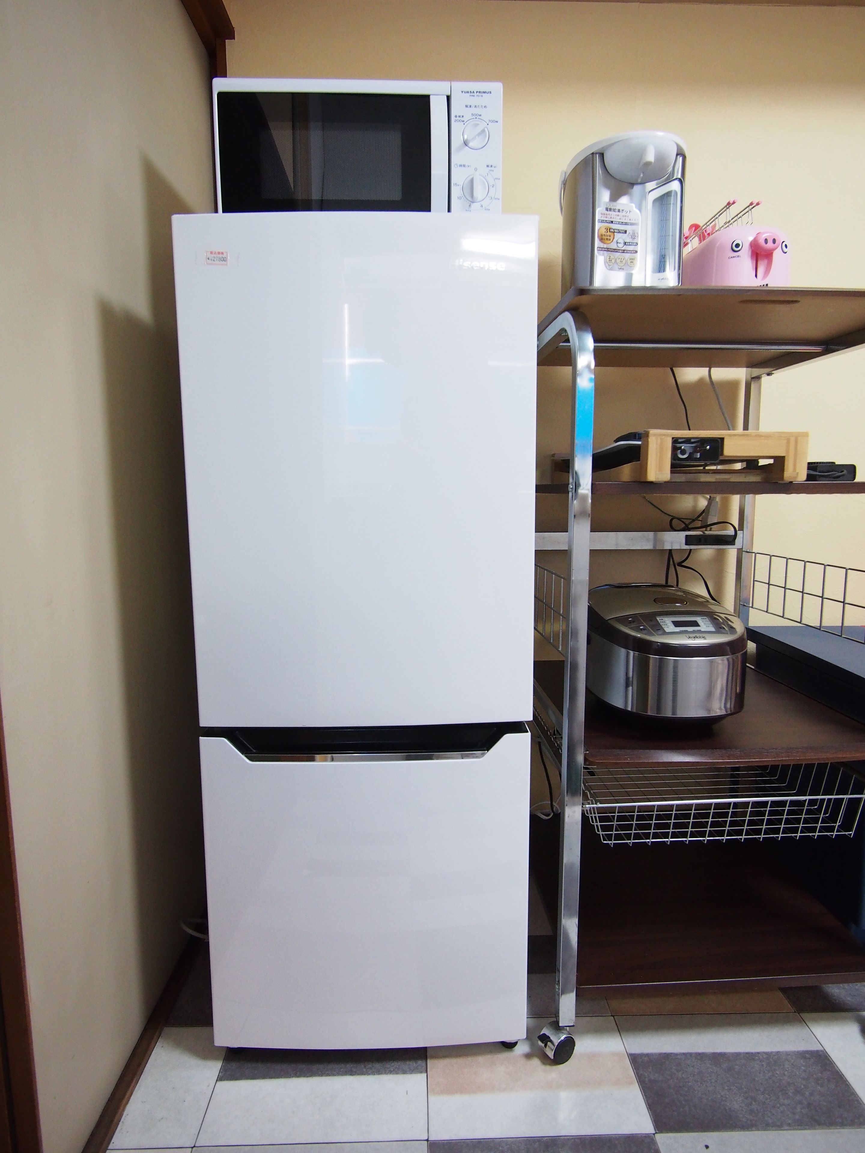 A kitchen with a white refrigerator, a microwave, a coffee maker, and a toaster on a wooden shelf.