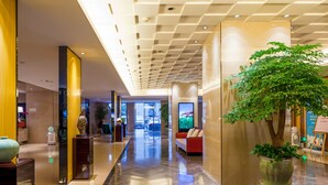 A modern hotel lobby with a polished marble floor, a reception desk, a seating area, and a large indoor plant. - Chongqing YiMei Hotel (Chongqing)