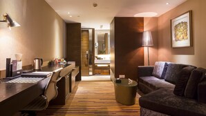 A hotel room with a desk, chair, sofa, and a trash bin. - Chongqing YiMei Hotel (Chongqing)