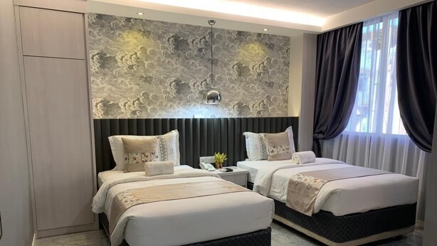 A modern hotel room with two beds, a marble floor, a textured wall, and a large window with curtains. - Red City Hotel (Lawas)