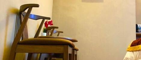 A dining area with wooden chairs and a table, a wall-mounted artwork, and a small potted plant.