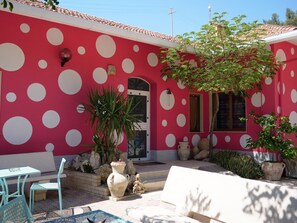 A building with a red exterior and white polka dots, a door, windows, and outdoor seating with chairs and tables. - B&B Vento di Scirocco (Favara)
