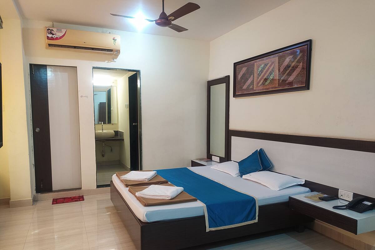 A hotel room with a bed, bedside table, and a mirror.