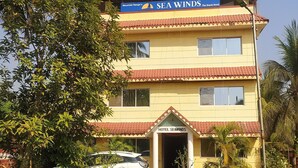 Un hotel de dues plantes amb teulada de rajola vermella i un rètol que diu "SEA WINDS The Beach Hotel".