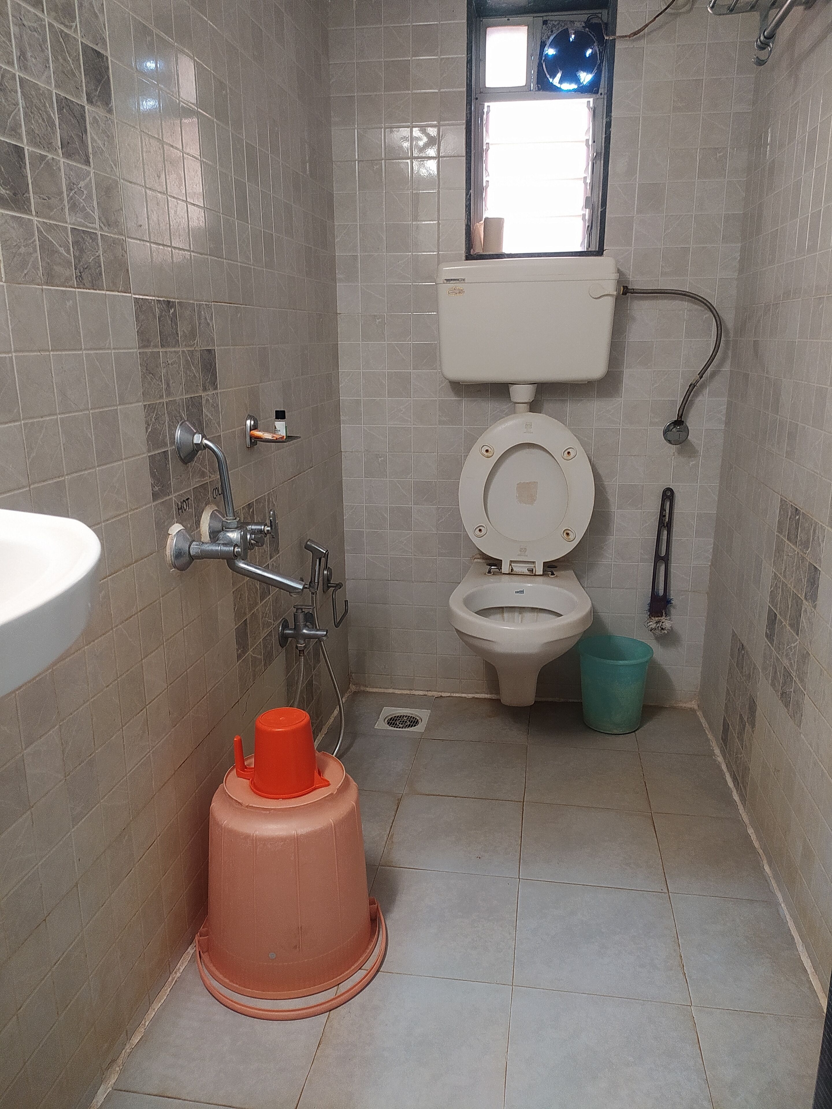 A small bathroom with a toilet, sink, shower, and a window.