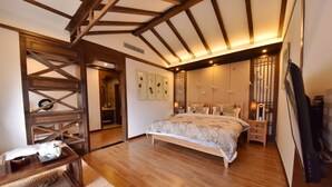 A bedroom with a wooden ceiling, a bed with patterned bedding, a nightstand, and a TV.